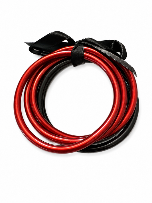 A pair of metallic bangles, red and black, coiled together and tied with a black ribbon on a plain white background.